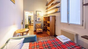 Ein kleines Zimmer mit Bett, Stuhl, Tisch, Heizkörper und Fenster.