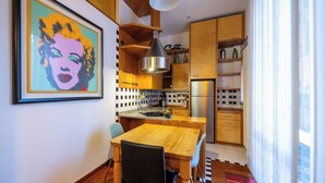 Eine moderne Küche mit Holzschränken, einem Edelstahlkühlschrank und einem Essbereich mit Tisch und Stühlen.