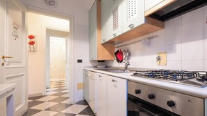 Een keuken met een gasfornuis, oven en witte kasten.