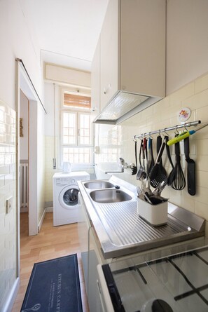 A modern kitchen with a built-in washing machine, stainless steel sink, and a utensil rack. - Busacchi (Bologna)