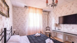 Ein Hotelzimmer mit einem Bett, einem Schreibtisch, einem Sessel, einem Fernseher und einer Kandelaber.