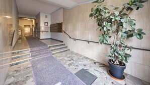Eine Hotelhalle mit einer Marmortreppe, einer Küstpflanze und einem Empfangsbereich.
