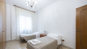 Ein Zimmer mit zwei Betten, einer Kristallleuchtre, einer Holztür und einem Fenster mit Vorhängen.