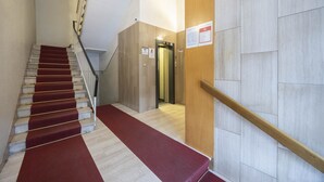 Eine Treppe mit rotem Teppich, einer Holzhandläufe und einer Wand mit einer Tür.