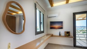 Une chambre moderne avec un banc en bois, un grand miroir, une télévision et une vue sur la ville.