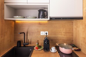 Uma cozinha com pia, cafeteira, chaleira e panela sobre o balcão.