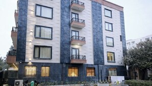 Ein mehrgeschossiges Gebäude mit Balkonen, einem gepflegten Rasen und blauem Himmel.