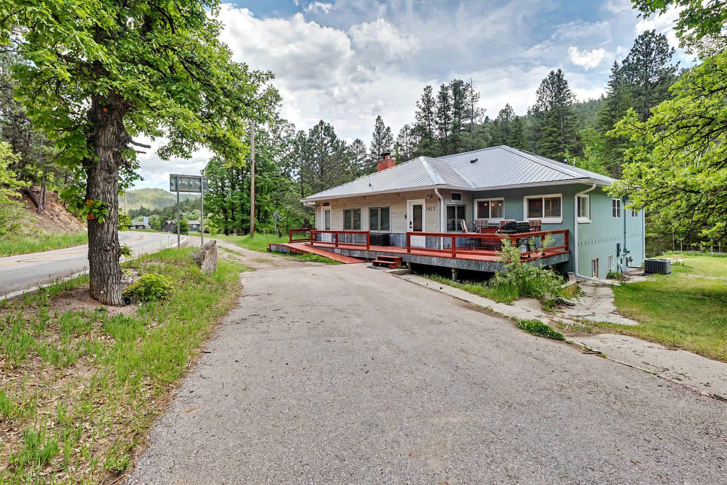 Ein zweistöckiges Haus mit Veranda, Auffahrt und Rasenfläche.