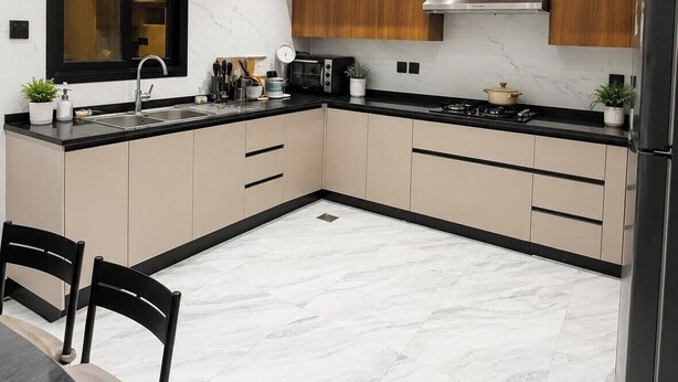 A modern kitchen with a marble floor, wooden cabinets, a black countertop, and a stainless steel range hood.