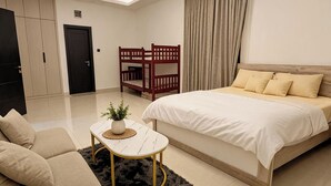 A modern hotel room with a bed, a sofa, a small table, and a bunk bed.