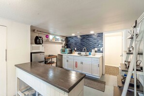 A compact kitchen with a central island, a microwave, a toaster, and a sink with a blue backsplash. - Cozy Studio with King Bed & Pet-Friendly Stay in Reno (Reno)