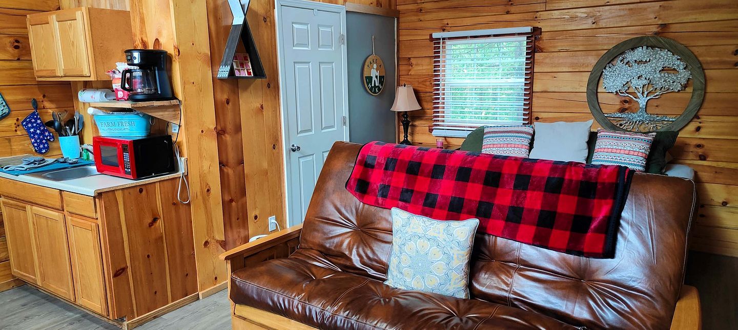 L’intérieur d’une cabine comprenant un coin cuisine, un canapé en cuir marron et une porte en bois.