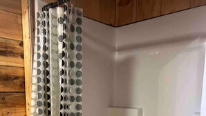 Eine Dusche mit durchsichtigem Vorhang mit kreisförmigen Mustern.