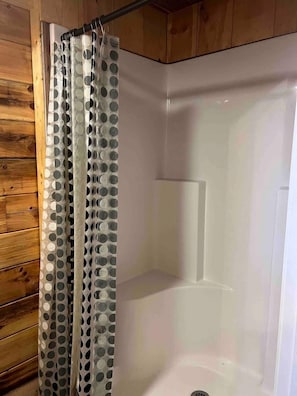 Une douche avec un rideau transparent orné de motifs circulaires.