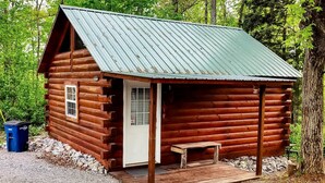 Eine Blockhütte mit Veranda, einer Tür und einer kleinen Bank.
