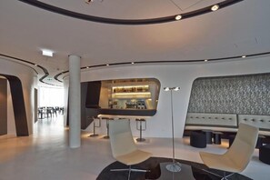 Un interior moderno con una zona de bar, asientos y una escalera.