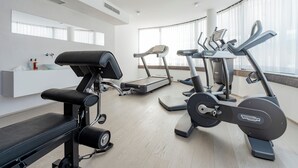 A modern gym with cardio machines, a bench, and a wall-mounted medicine cabinet. - Campus at Home (Planegg)
