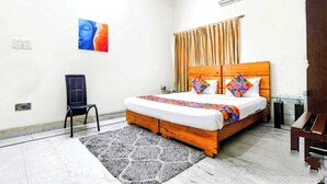 Un dormitorio con una cama de madera, una silla negra, un tapete gris y un cuadro en la pared.