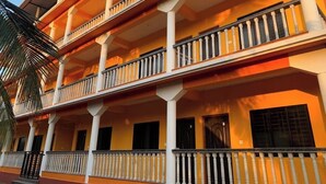 Un edificio de varios pisos con balcones, una palmera y cielo despejado.