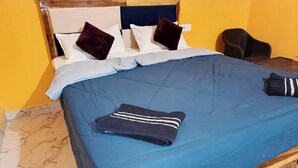 Una cama con una colcha azul, una toalla doblada y dos almohadas.