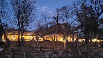 A historic building with stone walls and a balcony, surrounded by trees.