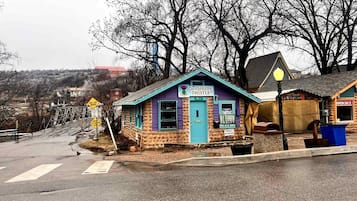 Un edificio pequeño con fachada púrpura y azul, un letrero que dice 'The Purple Thistle' y un escaparate con el letrero 'All Terrain Realty'.