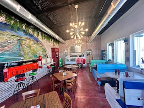 A restaurant with brick walls, a Chevrolet-themed bar area, and a mural of a landscape.