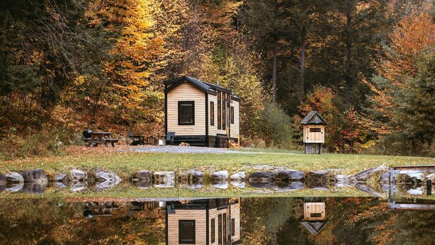 A cabin with a reflection in a pond, surrounded by autumn foliage. - Gorgeous Cedar Tiny House for a Unique Pet-Friendly Getaway in Chester, Vermont (Chester)