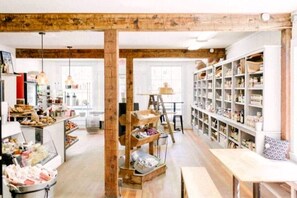 A rustic interior with exposed wooden beams, a central wooden ladder, and shelves filled with various items. - Gorgeous Cedar Tiny House for a Unique Pet-Friendly Getaway in Chester, Vermont (Chester)