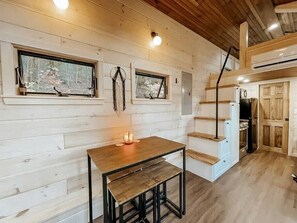 A wooden interior with a table, benches, and a staircase.