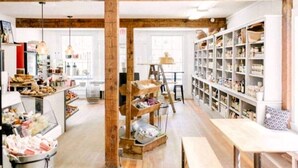 A rustic interior with exposed wooden beams, a central wooden ladder, and shelves filled with various items. - Gorgeous Cedar Tiny House for a Unique Pet-Friendly Getaway in Chester, Vermont (Chester)