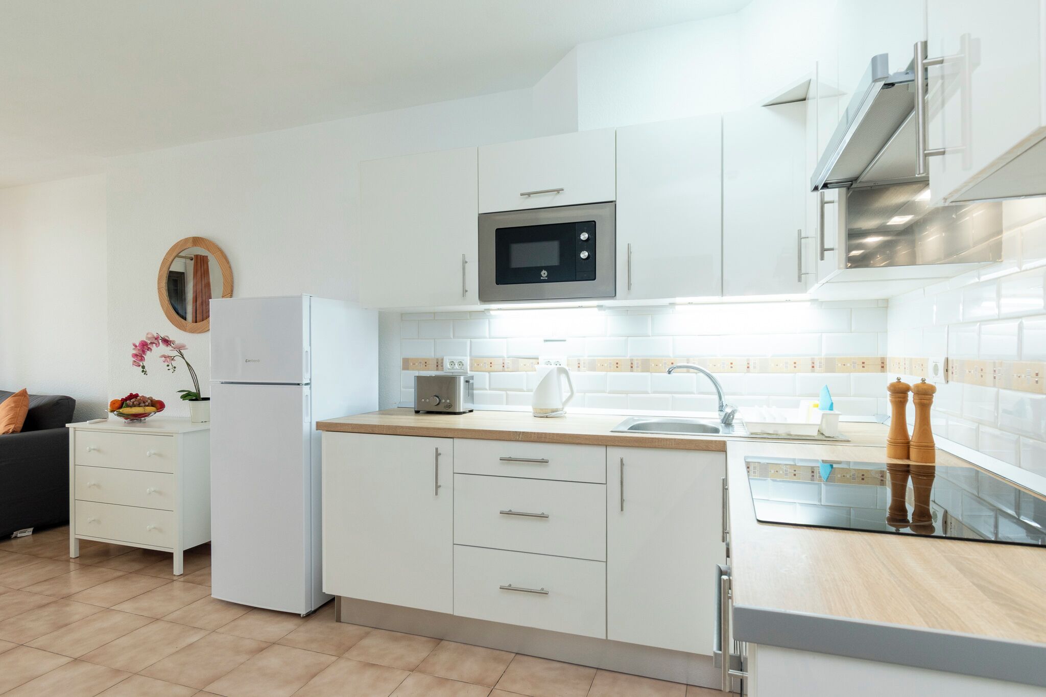 A modern kitchen with white cabinets, a microwave, a toaster, and a sink.