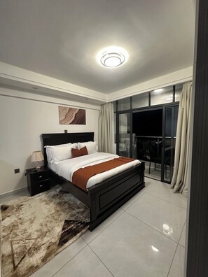 A modern bedroom with a bed, bedside table, lamp, and a view of the outside. - Modern 1 bedroom in Westlands near GTC|wi-fi|gym (Nairobi)