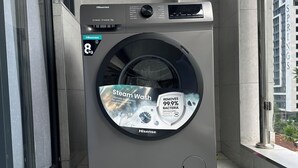 Hisensen 8 kg:n etukuormitettava pesukone parvekkeella, jolta avautuu näkymä rakennukseen, jonka kyltissä lukee ”MISTYS SPRINGS”.