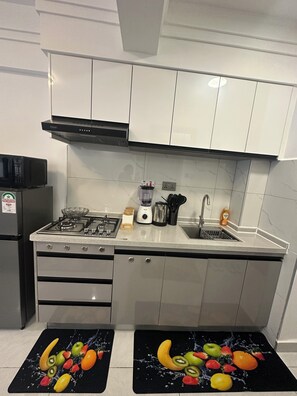 A kitchen with a gas stove, microwave, sink, and cabinets. - Modern 1 bedroom in Westlands near GTC|wi-fi|gym (Nairobi)