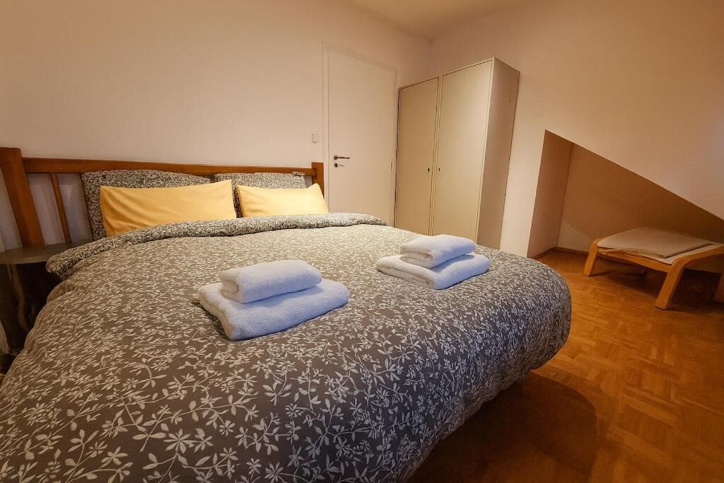 A bedroom with a bed, a wardrobe, and a chair.