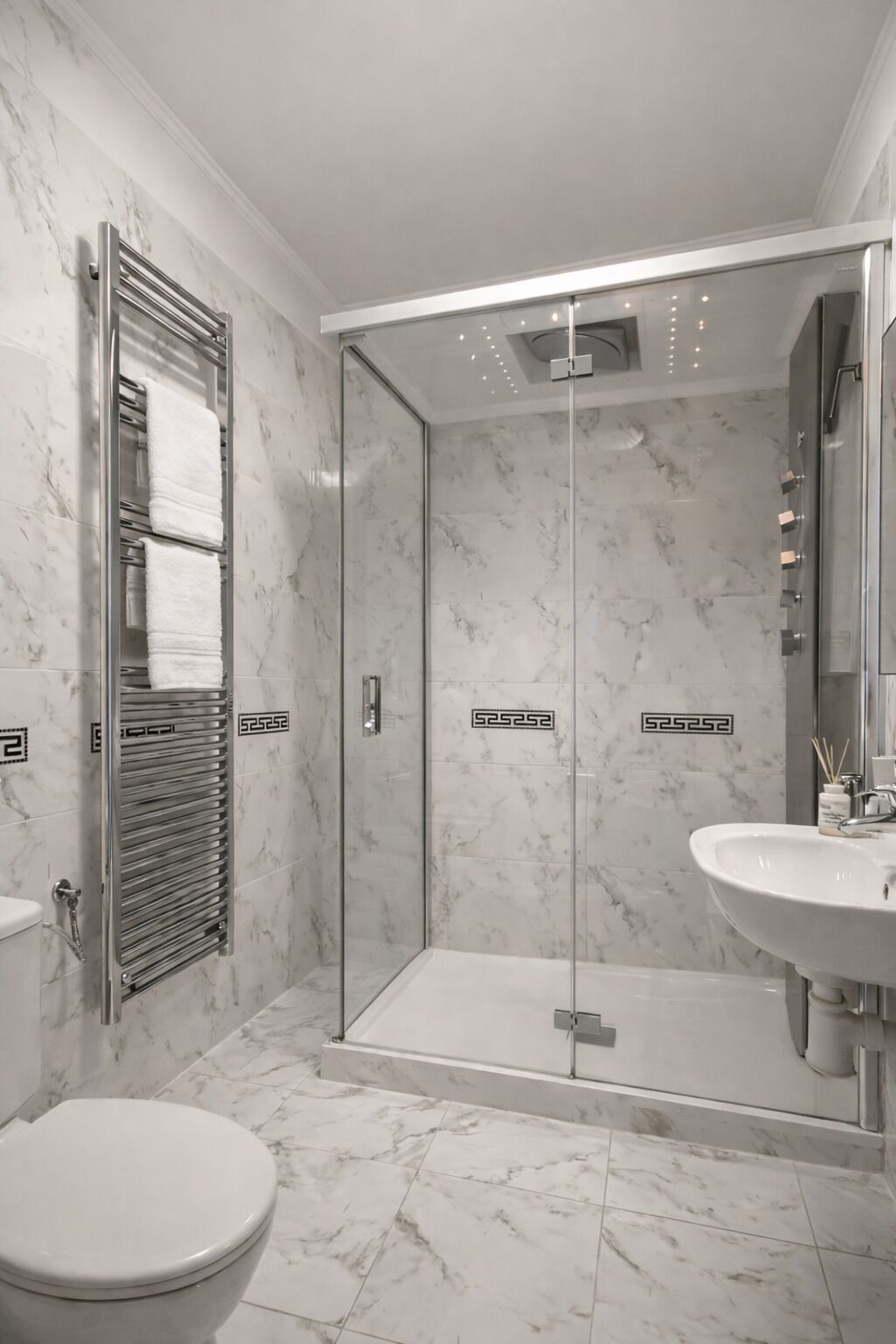 Une salle de bain avec une douche à parois de verre, un lavabo blanc et des toilettes.