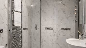 Une salle de bain avec une douche à parois de verre, un lavabo blanc et des toilettes.