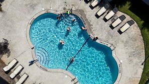 Piscina com trampolim e espreguiçadeiras ao redor.