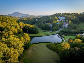 Un parcours de golf avec un lac, entouré d’arbres et de bâtiments.