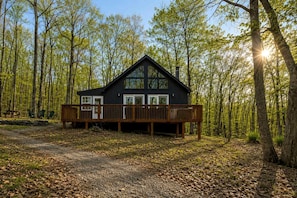 A cabin with a deck, surrounded by trees.