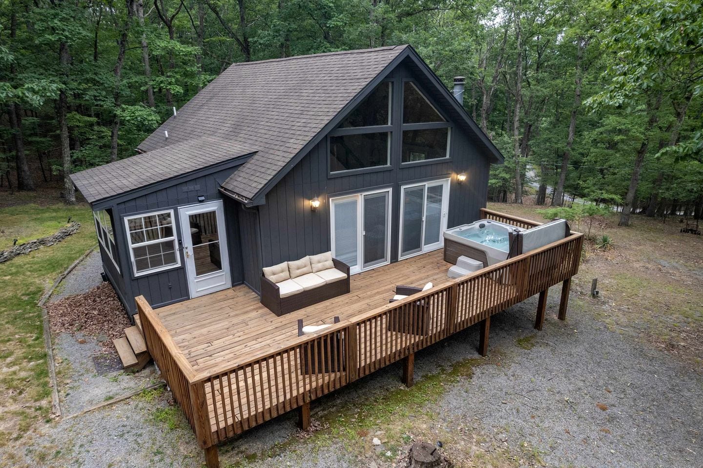 A cabin with a deck, a hot tub, and a large sliding glass door.