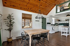 A modern kitchen with white cabinets, a wooden dining table, and black chairs.
