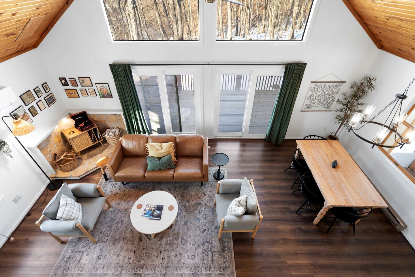 Ein geräumiger Loft mit hohen Decken, ein gemütlicher Wohnbereich mit einem braunen Ledersofa, einem Esstisch und einem großen Fenster mit Blick auf eine verschneite Landschaft.