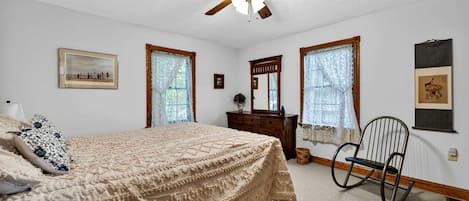 Un dormitorio con cama, cómoda, silla y ventilador de techo.