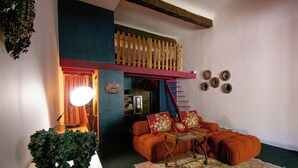 A cozy living room with a sofa, a coffee table, a staircase, and a potted plant. - Rare! Beautiful one-bedroom apartment with a garden in the heart of downtown Aix (Aix-en-Provence)