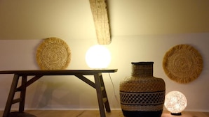 A room with a wooden table, a woven basket, a woven vase, and a spherical light fixture.