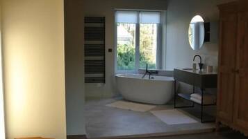 Une chambre à coucher avec un lit, une table de chevet, une fenêtre, une baignoire et un lavabo.