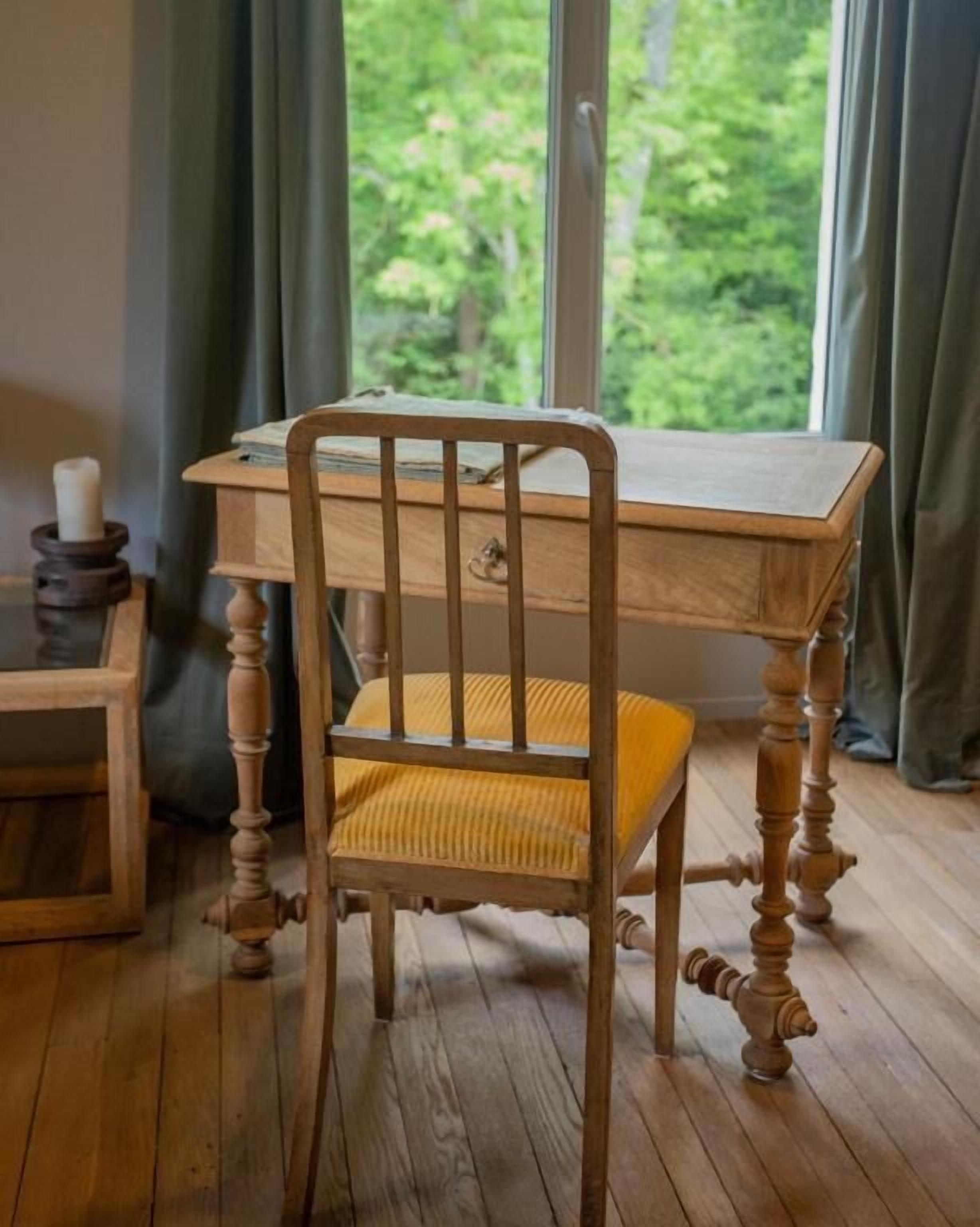 A wooden chair with a yellow cushion, a wooden desk, and a candle holder.