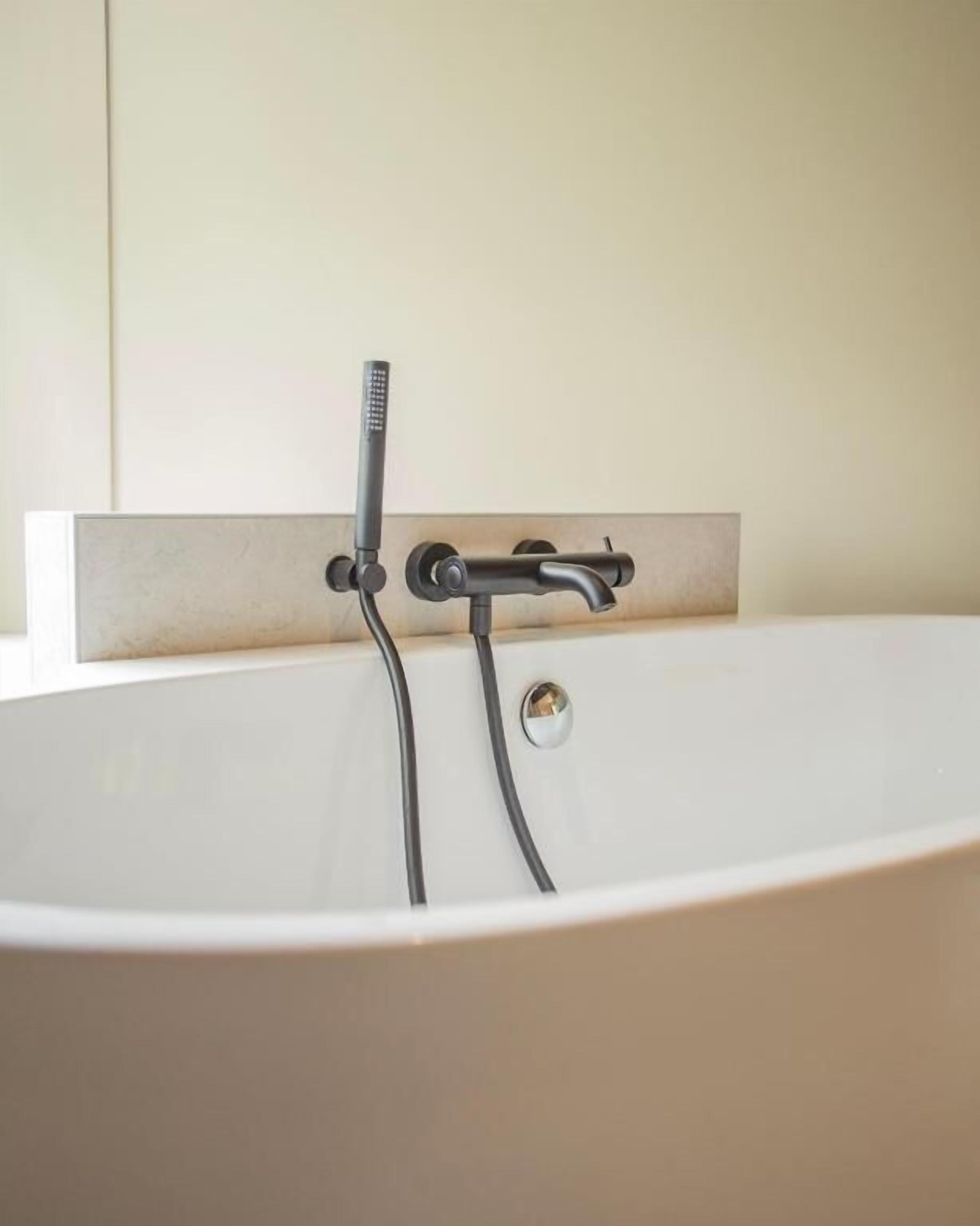 Une baignoire avec un robinet et une douchette à main.
